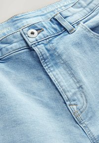 Jeans in denim azzurro chiaro con una vestibilità regolare, caratterizzati da una chiusura con bottone frontale, cuciture a contrasto e una leggera scoloritura sul tessuto.