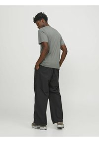 Camiseta de algodón gris con mangas cortas, combinada con pantalones negros de corte holgado y zapatillas grises, mostrando un ajuste relajado y un estilo casual.