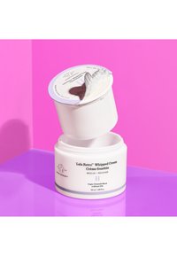 Whipped cream moisturizer in a white jar with a silver lid. Label features black text and illustrations, set against a bright pink background.