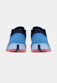 Zilā sporta apavi ar teksturētu virsu, jūras zila akcentiem un baltu vidējo zoli. Ar sarkanu zoli un rakstainu saķeri.