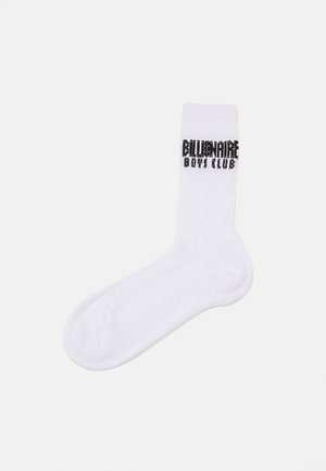 Chaussette en coton blanc de type crew avec une texture côtelée. Présente le logo noir "Billionaire Boys Club" en évidence sur le côté.