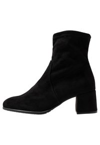Černé suede kotníkové boty s blokovým podpatkem střední výšky, špičatou špičkou a prošívanými detaily na boku. Hladký povrch a přiléhavý design.