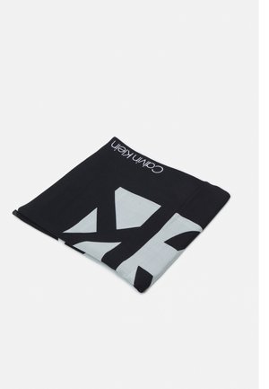 Czarnobiały złożony szalik Calvin Klein z dużymi wzorami liter i nazwą marki na jednolitym tle.