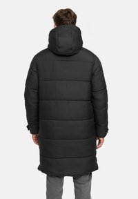 Zwarte gewatteerde jas met een capuchon, met een lange snit, horizontaal gestikte ontwerp en elastische manchetten. Eenvoudig en functioneel ontwerp.