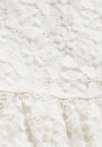Tissu en dentelle florale blanche avec motifs complexes brodés de fleurs et de feuilles sur fond en maille transparente.