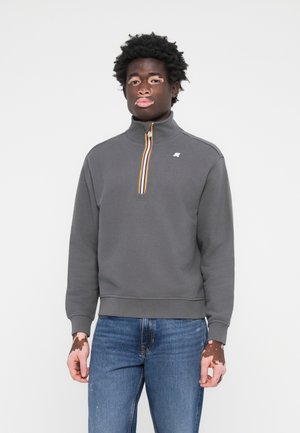 Grauer Reißverschluss-Sweatshirt mit hohem Kragen, ausgestattet mit einem bunten, gestreiften Reißverschluss. Hergestellt aus weichem Baumwollmaterial mit gerippten Bündchen und Saum.