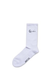 Biele bavlnené ponožky s krátkym strihom a rebrovaným lemom, s čiernym vyšitým logom a malým textom na spodnej strane. Hladká textúra, dizajn po členky.