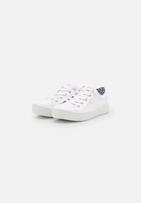 Valged kanva sneakerid ümmarguse varbaga, tekstureeritud kummitald ja kontrastsed oranžid silmad. Siseosa on vooderdatud mustrilise kangaga.