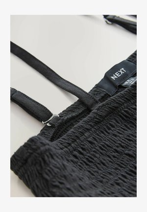 Černý smockovaný top s nastavitelnými ramínky a stříbrnými kovovými doplňky. Má strukturovaný povrch se sbíranými stehy a značkovou nášivku.