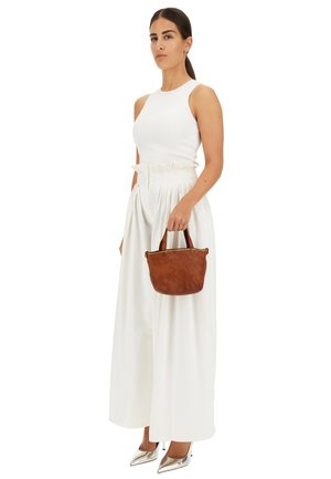 Top bianco senza maniche, pantaloni bianchi a vita alta, borsa in pelle marrone con borchie e décolleté argentati a punta. Texture morbide in tutto.