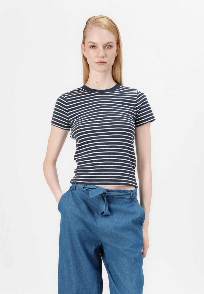 Gestreiftes T-Shirt aus navy- und weißen Baumwollstoff, mit kurzen Ärmeln, Rundhalsausschnitt, taillierte Passform, kombiniert mit lockeren Denim-Hosen.