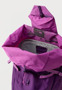 Violeta mugursoma ar auklas vāku, ar pelēku iekšpusi. Ārējai daļai ir gluda tekstūra un rūtainais raksts. Iekļauti metāla akcenti.