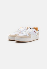 Hvide sneakers med grå ruskindsdetaljer, teksturerede mesh-paneler, flade snørebånd og en tan polstret krave. Gummisål med brun sålkonstruktion.