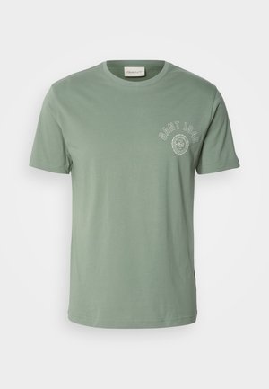 T-shirt di cotone verde chiaro con scollo rotondo, maniche corte e un design di logo circolare nella zona sinistra del petto.