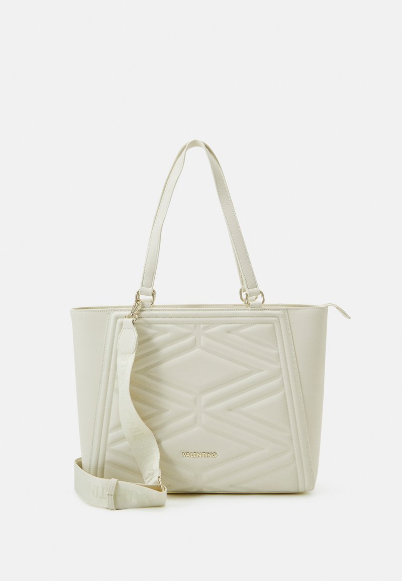 Sac fourre-tout beige clair avec un design matelassé géométrique, poignées doubles et bandoulière réglable. Présente un détail logo doré sur le devant.