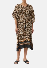 Sukienka w stylu kimono z wzorem ikat w brązie, czerni i kremie. Elastyczna talia ze sznurkiem, krótkie szerokie rękawy oraz detal w postaci frędzli.