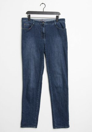 Granatowe, proste dżinsy z denimu wiszące na czarnym wieszaku na białym tle, z przednimi kieszeniami i zapięciem na guzik.