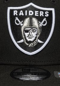 Black cap featuring an embroidered Raiders logo with a stylized pirate face, white accents, and a round black visor.