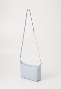 Borsa a spalla in pelle azzurro chiaro con una superficie liscia, forma rettangolare e manico decorato con catena dorata. Chiusura con zip nella parte superiore.