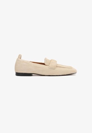Beige flat loafer with a textured, fur-like surface, black sole, and a wide strap across the upper part of the shoe.