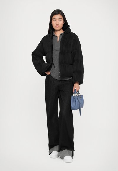 Black puffer jacket with a ribbed texture, gray polo, wide-leg black denim pants, white sneakers, and a small blue handbag.