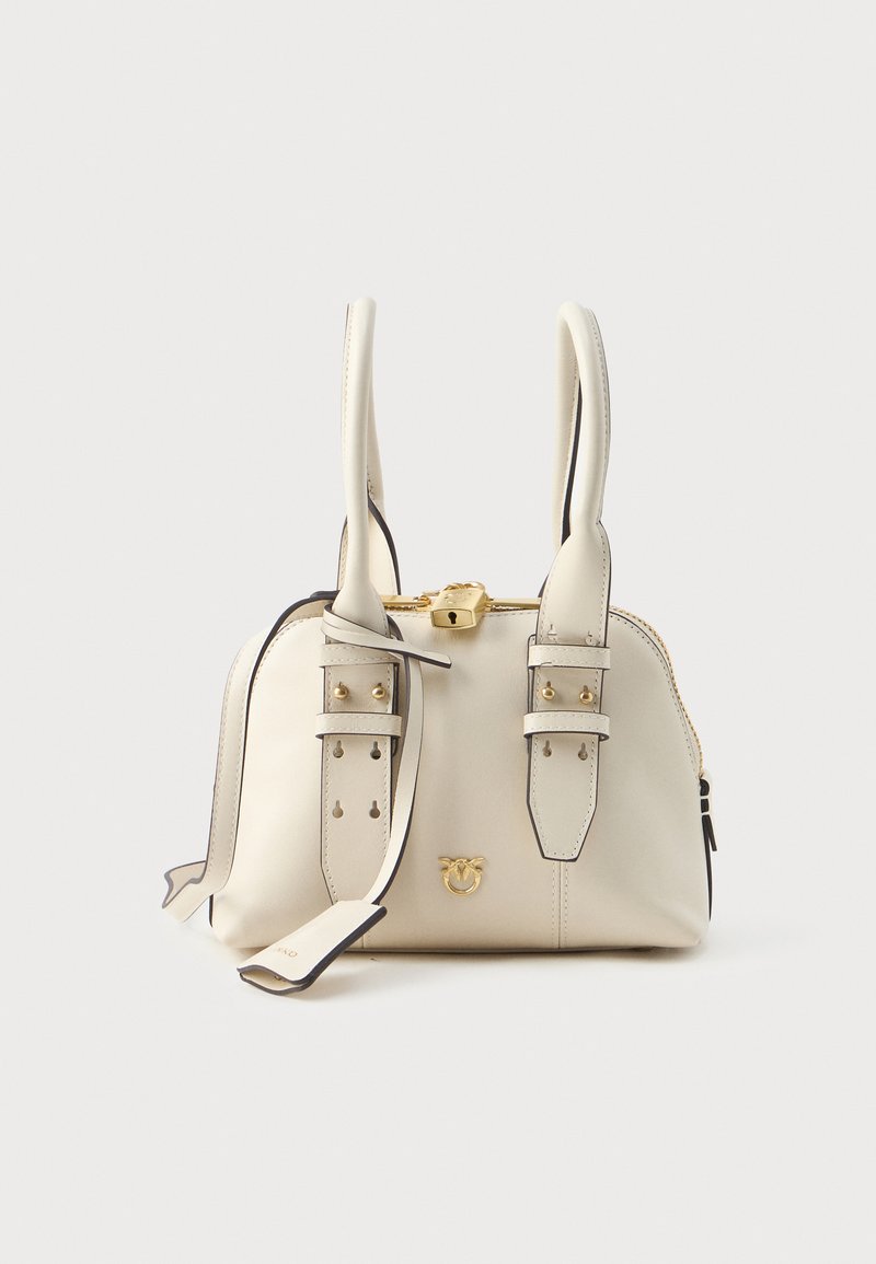 Saco de couro creme com forma estruturada, apresentando alças curtas duplas, ferragens douradas e tiras decorativas. Fecho de zipper na parte superior.