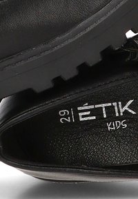 Zapatos de niños negros con parte superior de cuero texturizado, suela de goma y detalles de logo. Talla 29 indicada en la plantilla.