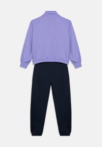 Μπλούζα λιλά με ψηλό γιακά και μανσέτες με ρίγες, συνδυασμένη με ναυτικά τζόγκερ με ελαστικές μανσέτες, σχεδιασμένα για άνεση και ευκολία.