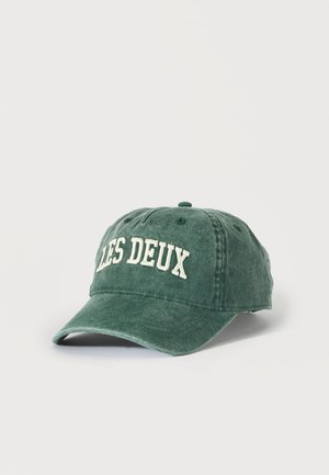 Grünes verblasstes Baseballcap mit weiß besticktem Text "LES DEUX" vorne, gezeigt vor einem einfachen hellen Hintergrund.