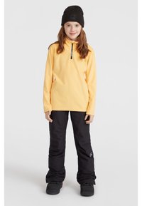 Gul fleece långärmad topp med kvartslång dragkedja; kombinerad med svarta isolerade byxor och svarta stövlar. Enkel design med minimala accenter.