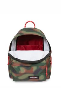Zaino camouflage con parte superiore arrotondata, foderato internamente di rosso e con dettagli in rosso sui cordini. Presenta una maniglia superiore e un'etichetta brandizzata.