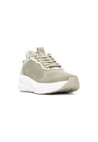 Zapatilla ligera con parte superior de malla transpirable en beige, detalles texturizados y suela intermedia blanca. Presenta cordones planos y una tira de sujeción trasera.