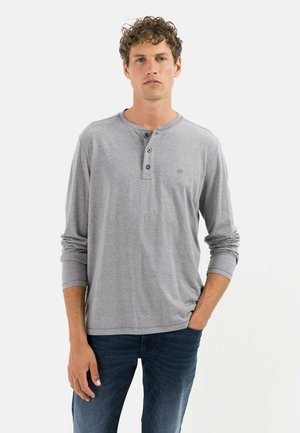 Szary longsleeve henley z trzema guzikami, zaokrąglonym dołem i miękką fakturą, w połączeniu z ciemnoniebieskimi dżinsami.