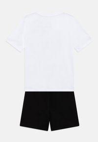 Ensemble en coton composé d'un t-shirt à manches courtes blanc et de shorts noirs. Design simple, sans motifs ni accents.