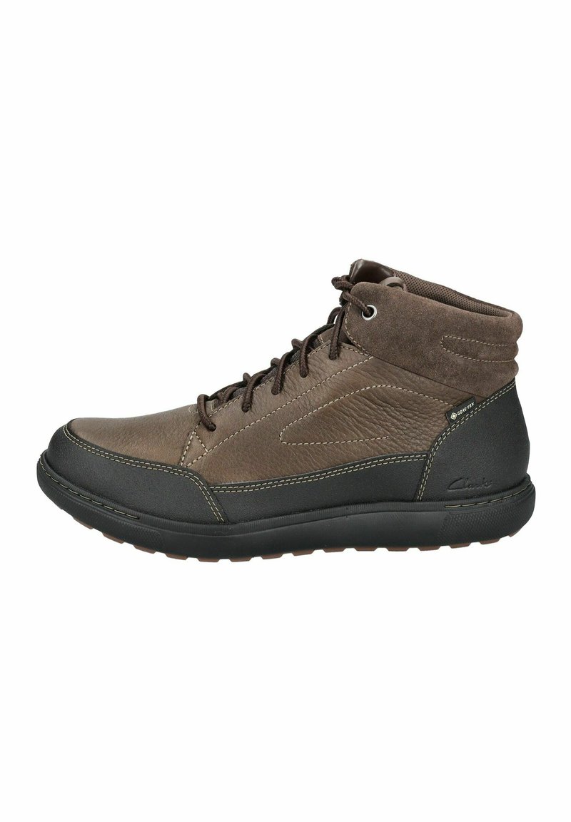 Botas de cuero marrón de media caña con suela de goma negra, diseño con cordones, colorín acolchado y detalles de costura en contraste. Indicación de característica impermeable.