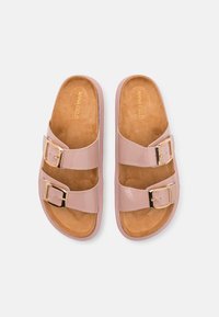 Sandales à glisser en vernis rose avec deux brides réglables à boucle, semelle intérieure rembourrée en tan et finition lisse, arborant un subtil logo doré.
