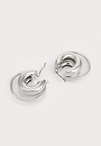 Silver hoop earrings featuring a spiraled design with a polished finish and a small hinge for fastening. Smooth texture, circular shape.