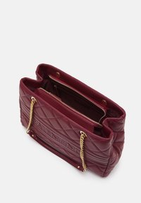 Vadderad bourgogne-handväska i glättat läder med detaljer i guldkedja, med en öppen topp och en dragkedjeficka inuti. Strukturen på utsidan visar varumärket.