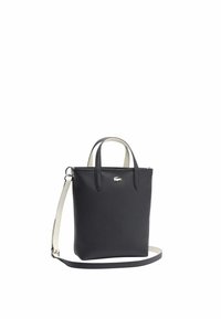 Sac à main en cuir texturé noir avec des poignées courtes et une bandoulière amovible. Présente un logo en métal argenté sur le devant.