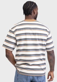 Striped short-sleeve t-shirt featuring horizontal lines in cream, brown, navy, and light blue; cotton material with a relaxed fit and ribbed neckline.