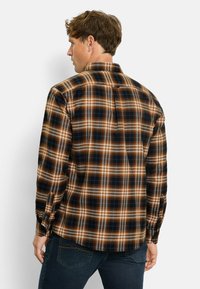 Langarm-Hemd aus Karostoff mit braunen, orangeroten und blauen Karomustern. Hergestellt aus gewebtem Stoff mit geknöpftem Manschette und klassischem Kragen.