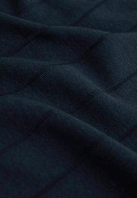 Tumši zilas krāsas teksturēta auduma ar smalku ribotu rakstu, demonstrējot mīkstas, gludas šķiedras un maigas krokas.