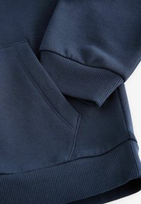 Sweat-shirt bleu marine avec des poignets et un ourlet côtelés, dotés d'une poche kangourou et d'une texture de tissu lisse. Des coutures détaillées sont visibles.