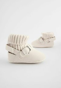 Beežid beebijalatsid, pehme kangast ülemise osaga, soonikkoes sääreosa ning külgmise pannaliga detail kindla istuvuse tagamiseks.