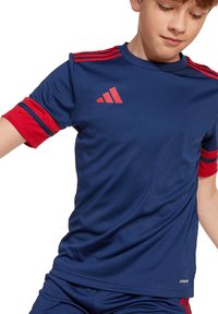 Marineblauw sport T-shirt met rode schouderstrepen en rode accenten. Gemaakt van ademende stof, voorzien van een ronde hals en een logo op de borst.