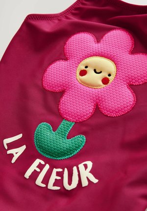 Magenta fabric featuring a large, textured pink flower with a smiling yellow center and green stem; includes the text "LA FLEUR" in white.