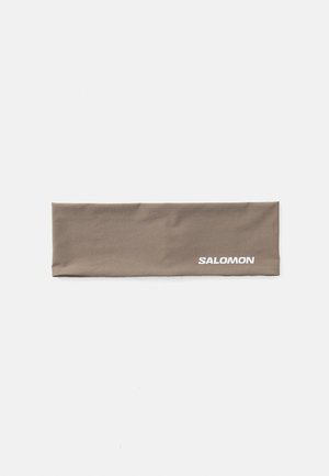 Brown fabric headband with a smooth texture. Features white "SALOMON" logo on one side. Rectangular shape, suitable for outdoor activities.