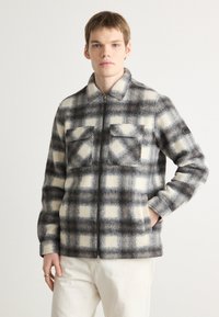 Men's plaid jacket made of wool blend fabric, featuring gray and white check pattern, zip closure, and two front pockets with flaps.
