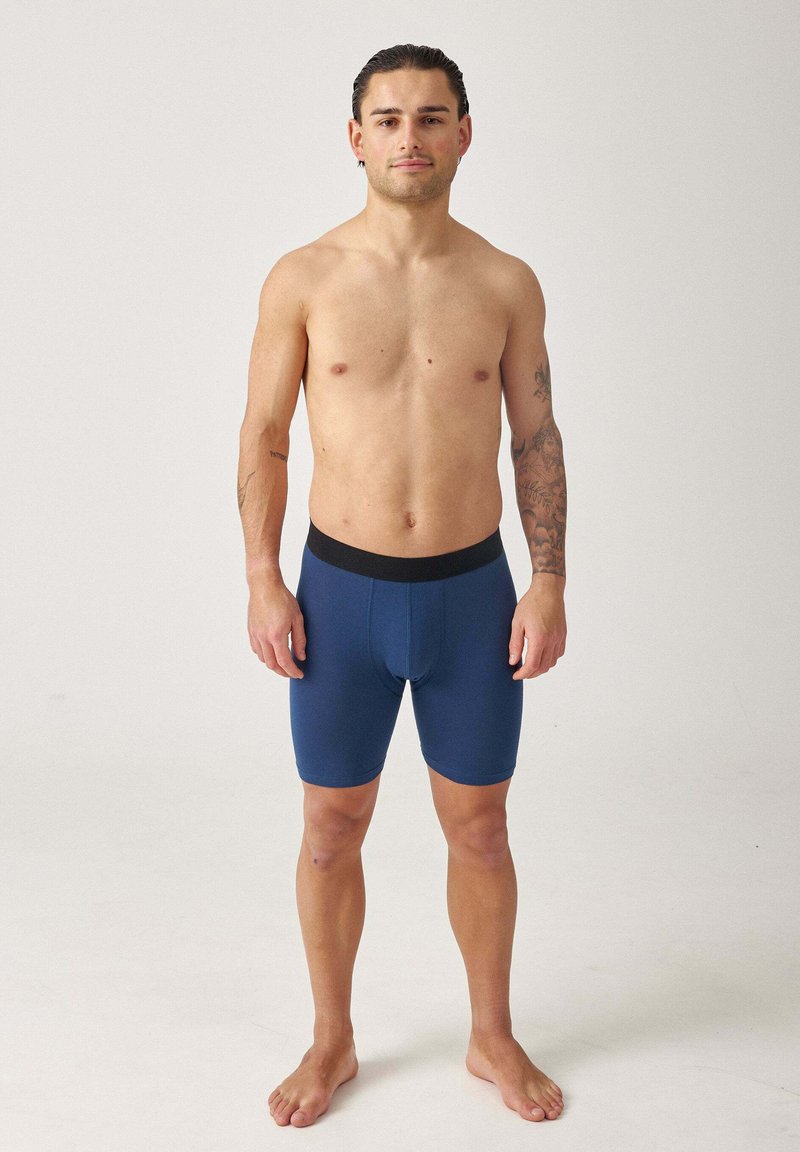 Männer Boxershorts in Blau aus weichem Material, mit einem schwarzen elastischen Bund, taillierter Passform und glatter Textur.