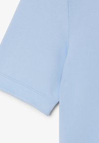 Camiseta de algodón azul claro con una textura suave, mangas cortas y costuras limpias a lo largo de los bordes. No hay patrones ni elementos de hardware visibles.